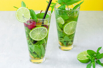 Non-alcoholic cold mojito in two glass glasses. Lemonade with lime and mint on a light background