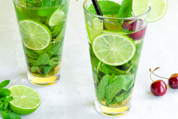 Non-alcoholic cold mojito in two glass glasses. Lemonade with lime and mint on a light background