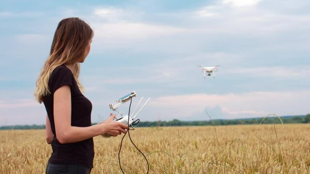 The female drone pilot walks into the field and inspects before the flight. Drone in women's hands