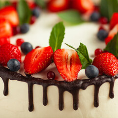 Close-up image of amazing wedding cake with fresh berries and dark chocolate topping. Natural light. Indoor shot