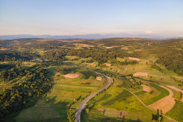 Aerial view from above on the country road in mountain range in between green grass and trees around - nature travel concept drone photo on Tresibaba in Europe Serbia in sunny summer day - Powered by Adobe