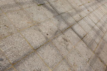 Perspective texture of street sideways floor with weathered square stone tiles