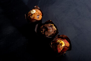 three muffins aligned diagonally, as seen from above, on a dark background