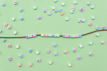 Words Best friends forever on green background made up of white cubes for making a friendship bracelet.