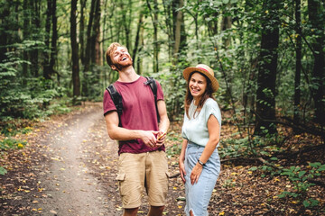 Young caucasian couple uses a smartphone to navigate in the forest. Hiking tourists orientation on the terrain using an online map, an application in a smartphone. GPS for building a route for a walk