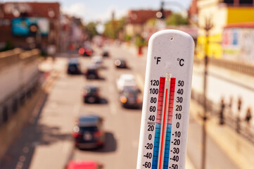 Thermometer in front of cars and traffic during heatwave in Montreal.