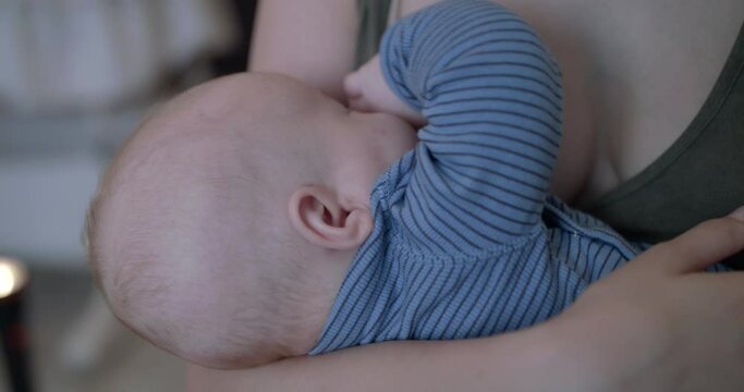 Close view of breastfeeding a cute, little baby boy in room at camera