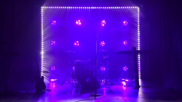 Classic retro chrome microphone and electric guitar together with drums and piano synthesizer keyboard on the stage in dark studio with smoke and neon lighting. Dynamic blue neon lighting effects