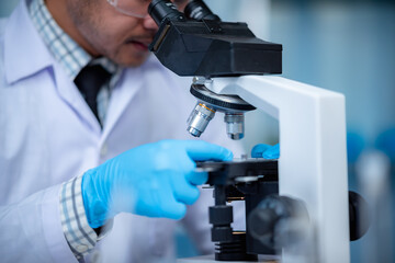 Young scientist looking through a microscope in a laboratory. Young scientist doing some research.