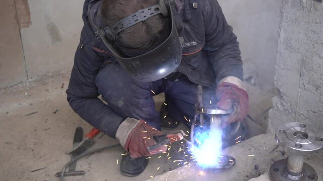 Close-up welder working with electrode at semi-automatic arc welding in manufacture production plant.Bright sparks from welding