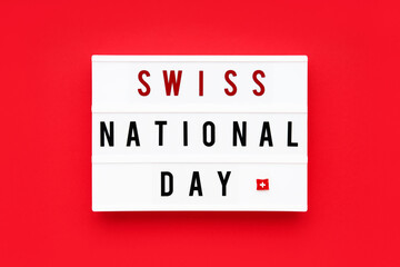 SWISS NATIONAL DAY written in a lightbox on a red background. Independence day date. Top view