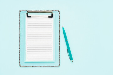 Blank clipboard mockup and ballpoint pen on light blue color background. Top view, copy space. Back to school, deadline, morning concept.