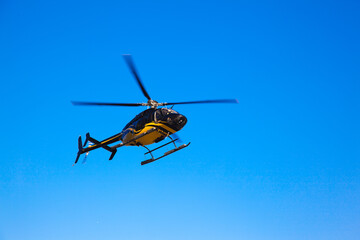 The isolated black yellow helicopter flying in the sky.
