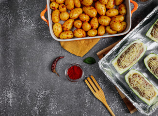 Potatoes with stuffed zucchini on the stone
Young potatoes with stuffed zucchini in glass dishes lie on the right on a stone background with space for text on the left, top view.