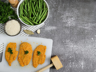 ingredients for cooking
Chicken fillet chops with rice and vegetables lie on the left on a stone background with space for text on the right, top view.