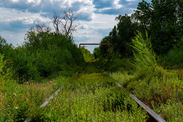 Fototapeta na wymiar Ukraine, Krivoy Rog, the 16 of July 2020. Rarely used rail tracks near the town park under beautiful sky.