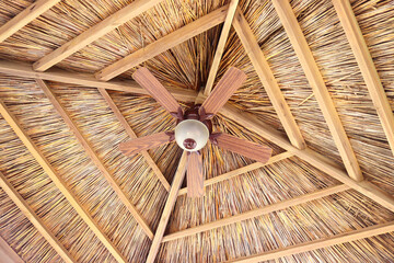 A ceiling view of tiki hut with ceiling fans