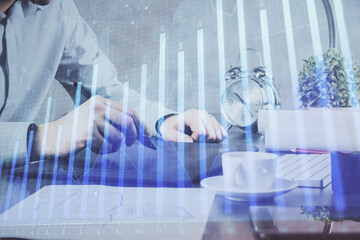 Double exposure of man's hands holding and using a phone and financial graph drawing. Analysis concept.