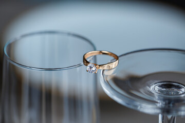 A wedding ring made of precious metal with a diamond stone lies in a glass
