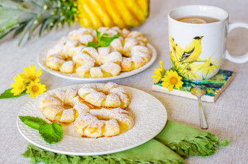 Pineapple puffs decorated with mint leaves next to tea and pineapple