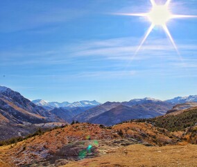 View of mountains with snow from Queenstown Hill in New Zeeland with blue sky and the sun looking like a star