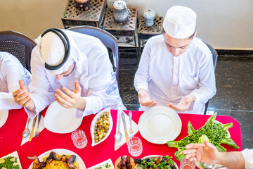 Happy Arabic Muslim family praying to god prior eating and asking for god forgiveness