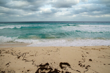 Vacations. Tropical seascape. Turquoise color water sea. The white sand and ocean waves under a dramatic stormy sky in Cancun, Mexico.