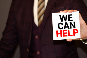 Paper note pinned to a cork notice board with the phrase We Can Help typed onto it