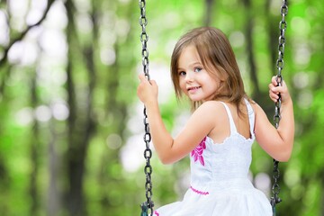 Little child blond girl having fun on a swing