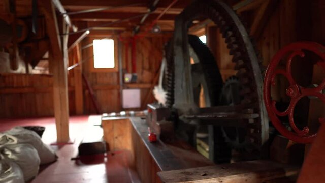 Panning view of huge steel cogwheel inside of old watermill.
