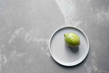 Variegated pink lemon or pink-fleshed Eureka lemon in plate on concrete background with copy space, top view