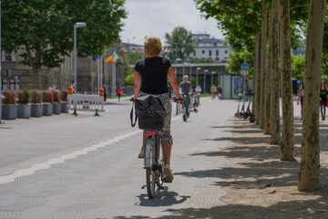 Female cyclist ride bicycle on bicycle lane on promenade riverside of Rhein River in Düsseldorf, Germany. Cycling friendly city in europe. Eco friendly mobility transportation.