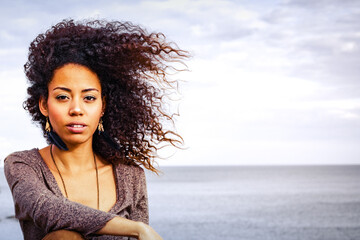  an afro American girl with a beautiful curly hair outdoors looking at the camera with copy space