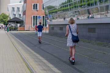 People ride E-scooters, trendy urban transportation with Eco friendly sharing  mobility concept, on bicycle lane at promenade riverside of Rhine River at medienhafen in Düsseldorf, Germany.