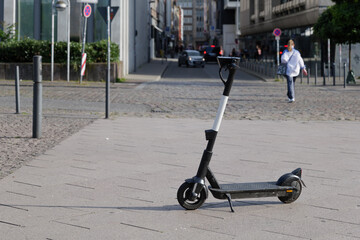 Selected focus at E-scooter or Electric Scooter by startup company with concept of Eco friendly mobility urban lifestyle, park on sidewalk in Downtown Düsseldorf, Germany.