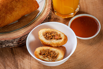 Brazilian appetizer deep fried beef croquette with pepper sauce and orange juice - Risolis