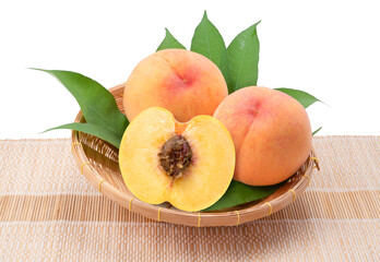 Korean Golden Peach fruits on Bamboo basket isolated on white. Fresh Honey Yellow Peach with leaves isolated on white background.