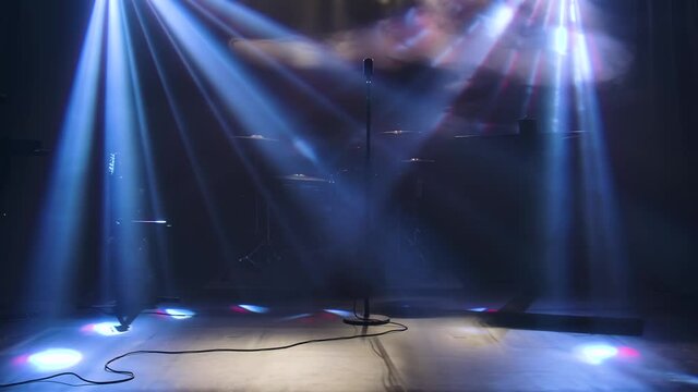 Classic retro chrome microphone and electric guitar together with drums and piano synthesizer keyboard on the stage in dark studio with smoke and neon lighting. Dynamic purple neon lighting effects