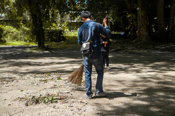 Gardening workers sweeping the leaves that fell on the ground. During the dry season Background