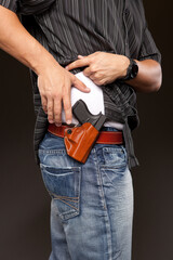Man lifts his shirt and is about to draw his concealed carry pistol.