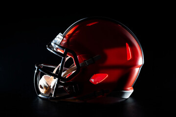 Professional gear and competitive sports concept with dramatic low key photograph of American football helmet with face mask in the dark isolated on black background with clipping path cutout