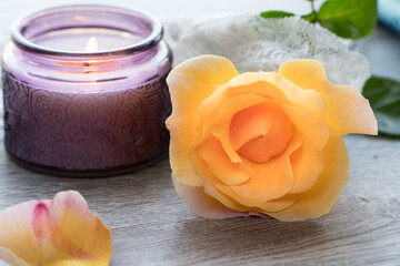 Yellow rose with purple candle on lace. Spa setting or Mother’s Day and Valentine’s Day concept.