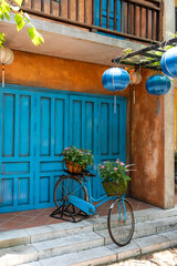 Fototapeta na wymiar Vintage bike with basket full of flowers next to an old building in Danang, Vietnam, close up
