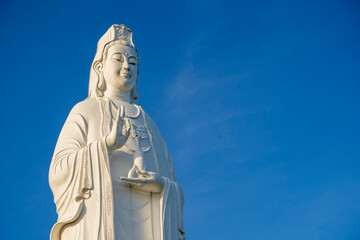 Detail of Lady Buddha statue in a Buddhist temple and blue sky background in Danang, Vietnam. Closeup, copy space