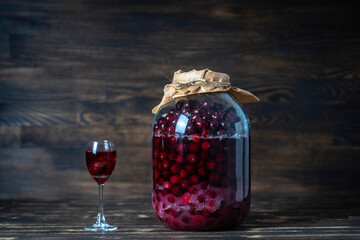 Homemade tincture of red cherry. Berry alcoholic drinks concept. Red wine made from ripe cherries in a large glass jar and a wineglass