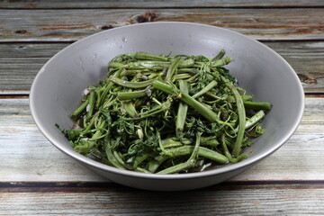 Traditional fried and stirred green Water mimosa seasoning with soy sauce and pepper on the plate. Famous vegetarian side dish menu with porridge in Asia restaurant. High fiber and low fat menu. 