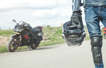 Fototapeta na wymiar Caucasian biker holding helmet. Hobby. Sport. Speed