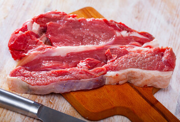 Obraz premium Raw beef entrecote steak ready for cooking on wooden surface. High quality photo