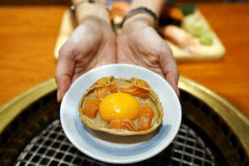 A shell crab of kani miso topped with fresh salmon and yolk egg, Japanese traditional food.