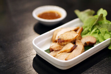 Charcoal-boiled pork neck (grilled pork) served with spicy dipping sauce (Jaew), Thai food recipe.